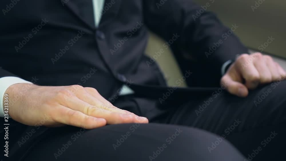 Man in suit looking at watch and nervously knocking on knee by hand, hurry up Man in suit looking at watch and nervously knocking on knee by hand, hurry up