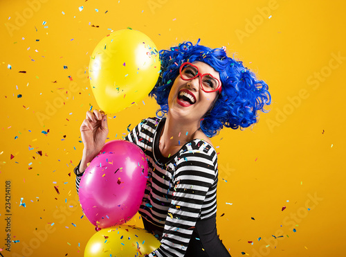 Colorful fun portrait of happy woman holding balloons and playing in confetti