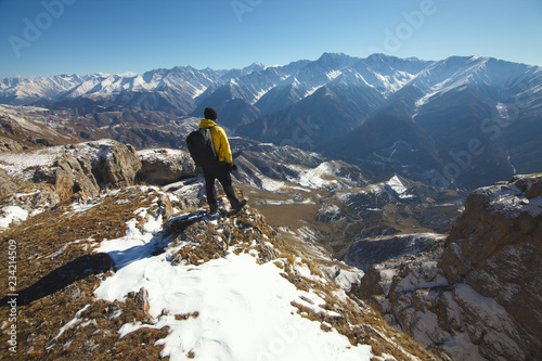 A traveler at the top of the mountain observes the surrounding landscape.