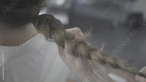 Hairdresser makes, plaiting braids for young woman on her wedding day