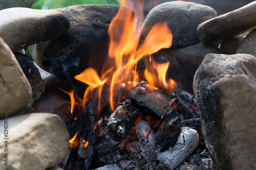 Campfire sourrounded by stones to keep the fire. Wood burning. Bonfire. Flame. Closeup