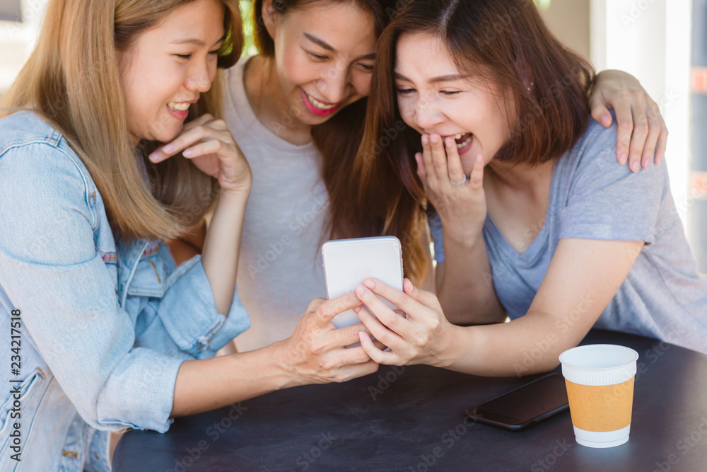 Cheerful asian young women sitting in cafe drinking coffee with friends and talking together. Attractive asian woman enjoying coffee while using smartphone for talking, reading and texting. Cheerful asian young women sitting in cafe drinking coffee with friends and talking together. Attractive asian woman enjoying coffee while using smartphone for talking, reading and texting.