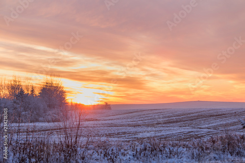 Beautiful winter sunset. The first snow in the fields at sunset.