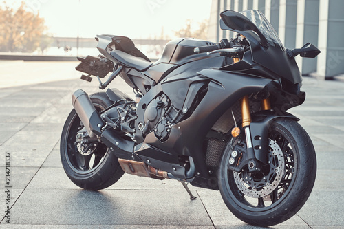 Close-up photo of a black superbike outside near building. photo