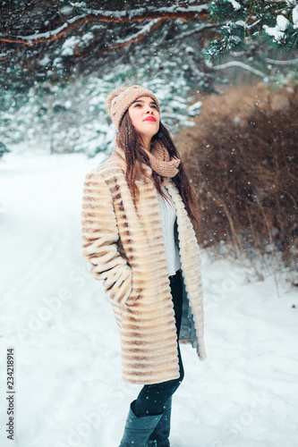 happy young woman walking under the pine trees in snowy winter forest. Seasonal activities and winter vacations concept