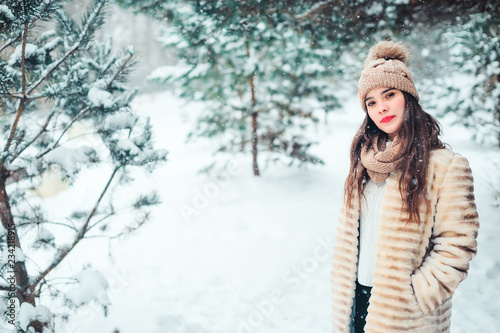 happy young woman walking under the pine trees in snowy winter forest. Seasonal activities and winter vacations concept © mashiki