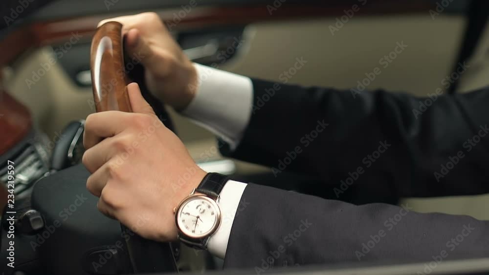 Man in suit sitting on driver place and holding steering wheel, new car purchase Man in suit sitting on driver place and holding steering wheel, new car purchase