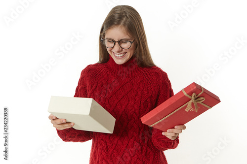 Joy, celebration, happiness and holiday concept. Overjoyed pleased young birthday girl posing at white wall with open fancy box, looking inside with excitement and pleasure, rejocing at new gadget photo