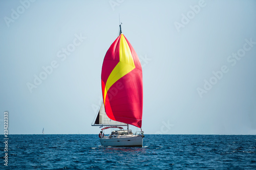 Luxury yacht with red sails at Regatta. Sailing in the wind through the waves at the Sea.
