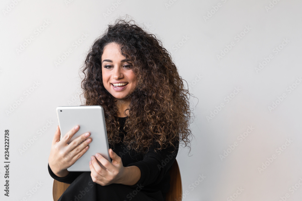Beautiful woman with curly hair dressed on black working or shopping using computer or tablet Beautiful woman with curly hair dressed on black working or shopping using computer or tablet