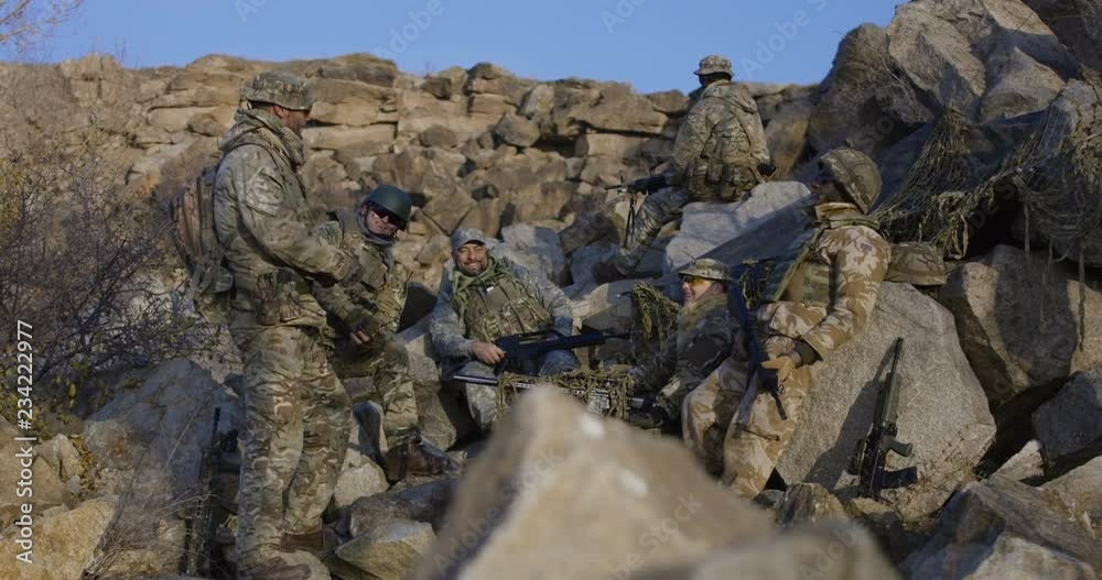 Medium slow motion shot of soldiers taking a break and playing with a grenade and laughing Medium slow motion shot of soldiers taking a break and playing with a grenade and laughing