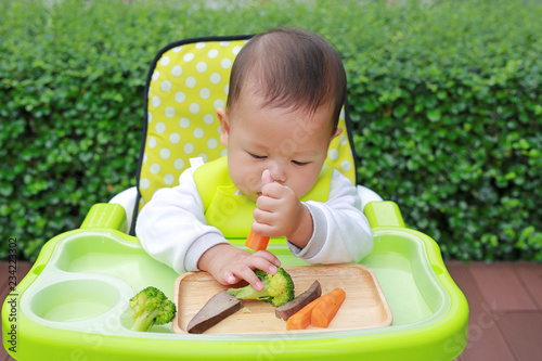 Asian infant baby boy eating by Baby Led Weaning (BLW). Finger foods concept. photo