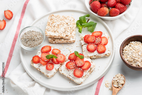 Rice crispbread with strawberries and curd cheese ricotta on white plate. Healthy snack, vegetarian food, healthy sweet appetizer or breakfast concept