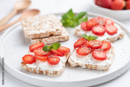 Healthy rice crispbread snack with curd cheese and strawberries on white plate. Healthy sweet snack, vegetarian snack