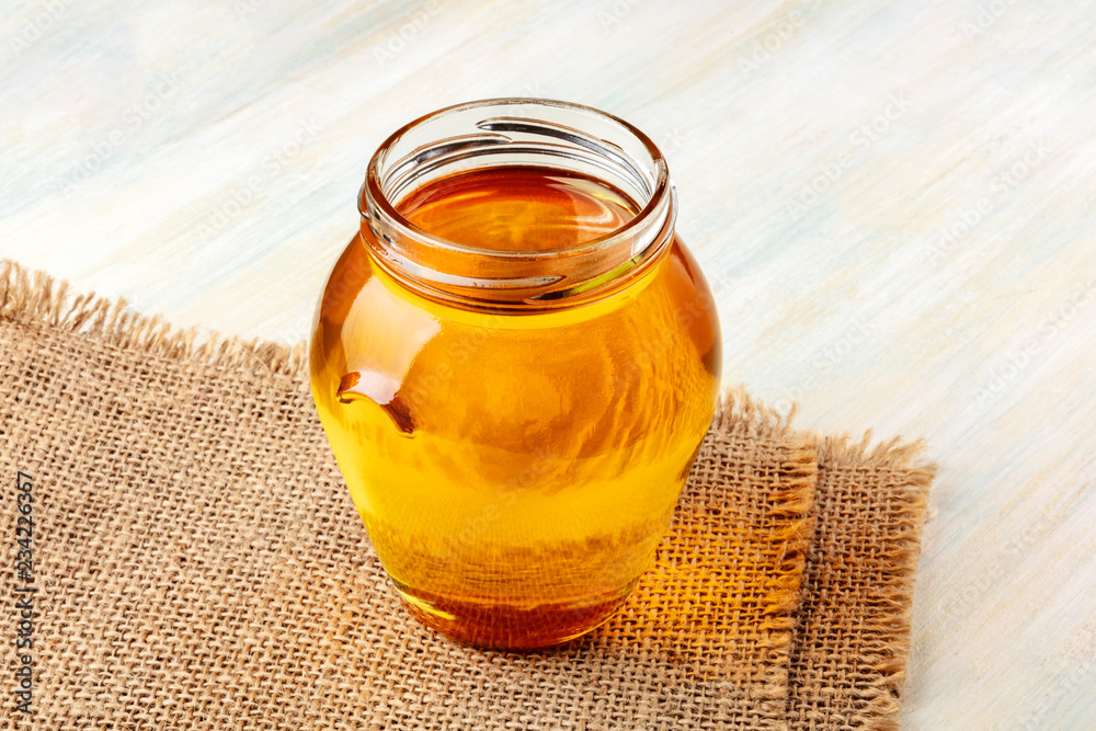 A photo of a vibrant jar of organic honey on a rustic background with a place for text A photo of a vibrant jar of organic honey on a rustic background with a place for text