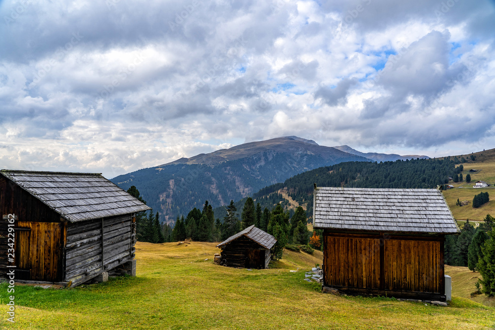 Obraz premium Wooden shed on a grassy meadow in a mountains.