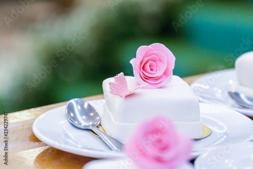 White cupcakes decorated with pink flowers. © Sunisa