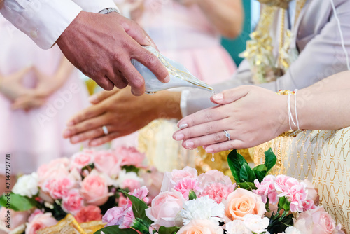 Thai wedding,Close up of hands pouring water into the hands. © Sunisa