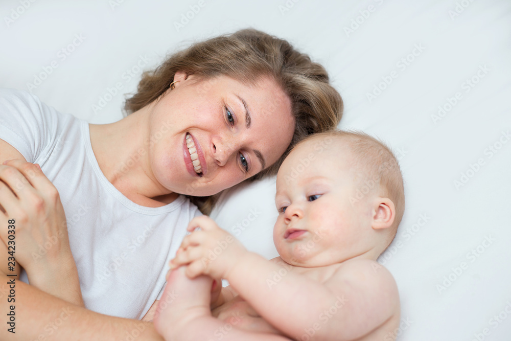 mother is playing with her baby son in the bedroom mother is playing with her baby son in the bedroom