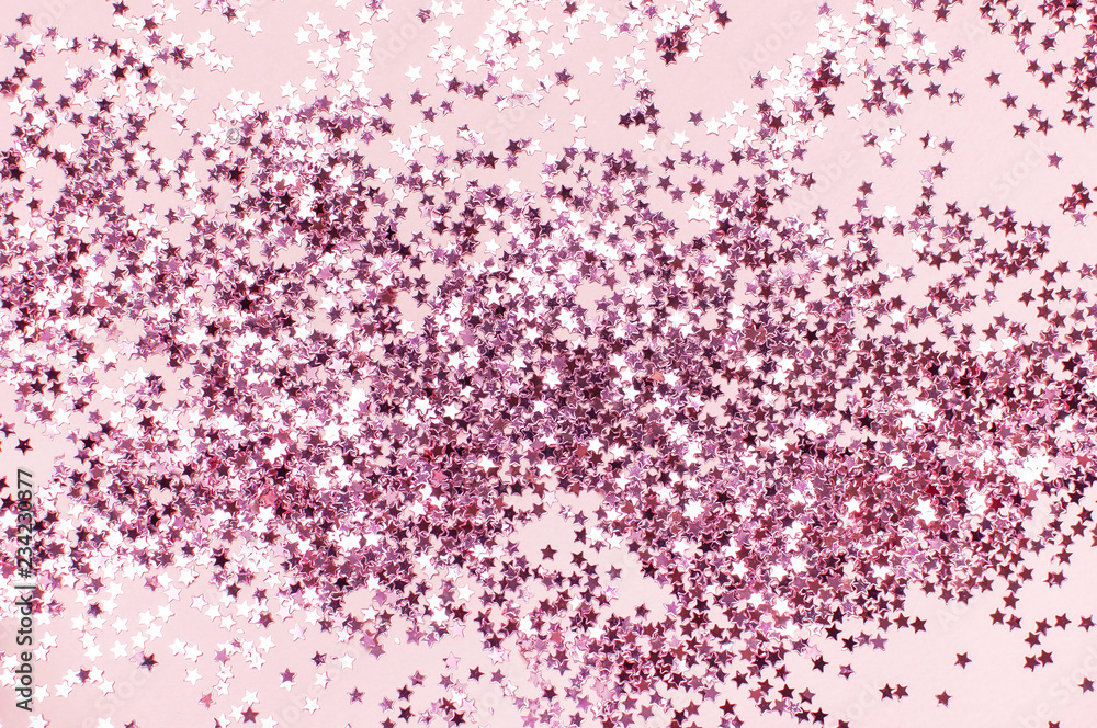 Pink holographic glitter confetti in the form of stars on pink background Flat lay top view copy space. Festive holiday pastel backdrop. Birthday, congratulations, Christmas, New Year