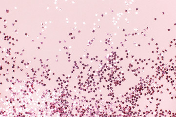 Pink holographic glitter confetti in the form of stars on pink background Flat lay top view copy space. Festive holiday pastel backdrop. Birthday, congratulations, Christmas, New Year