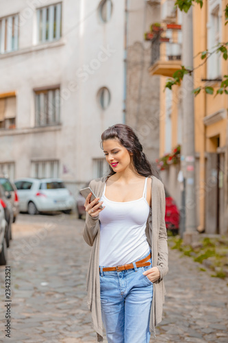 Cute young woman using cellphone in urban surroundings.