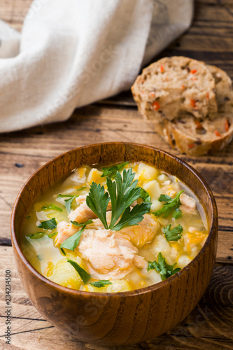 Fish soup in a wooden bowl with fresh herbs.