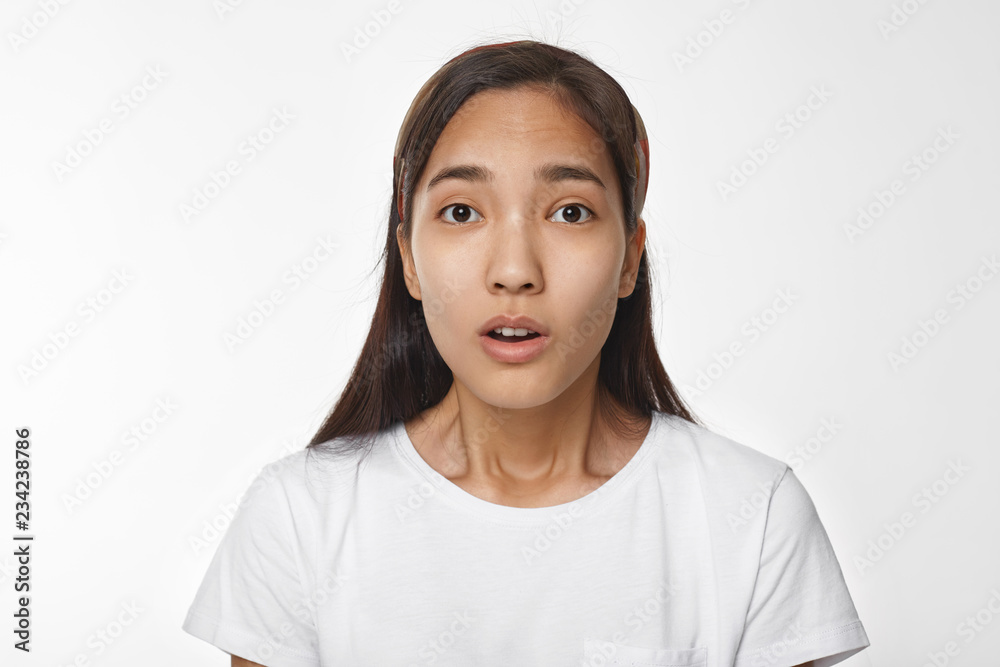 Dark haired young Korean woman in white t-shirt opening mouth, having ...