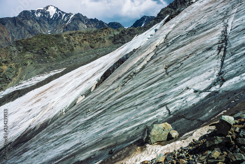 Snow on giant mountain ridge. Wonderful ice terrain on mountainside. Icy steep slope. Amazing snowy rock. Climb high in mountains. Atmospheric minimalist landscape of majestic nature of highlands.