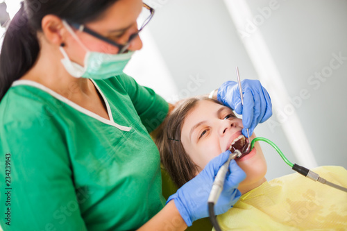 Dentist is repairing teeth of a little girl.