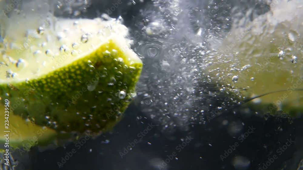 Macro close-up,refreshing soda tonic fizzy water, lime in Glass, ice. Slice of lemon, mineral bubbles. Detox or thirst concept. Healthy, dietary nutrition. Cold lemonade mojito drink. Black background