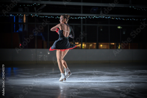 An ice skater is spinning on the ice during her performance. She looks gorgeous and her performance is magnificent.
