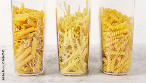 Different types of raw pasta in containers. Storage products at home. Fettuccine, fusilli, penne