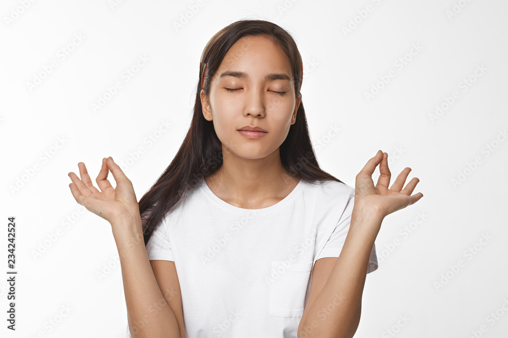 © shurkin_son - Meditation, concentration, harmony and balance concept. Studio image of brunette Chinese girl closing eyes and holding hands in mudra gesture, having calm peaceful restful look while meditating © shurkin_son - Meditation, concentration, harmony and balance concept. Studio image of brunette Chinese girl closing eyes and holding hands in mudra gesture, having calm peaceful restful look while meditating