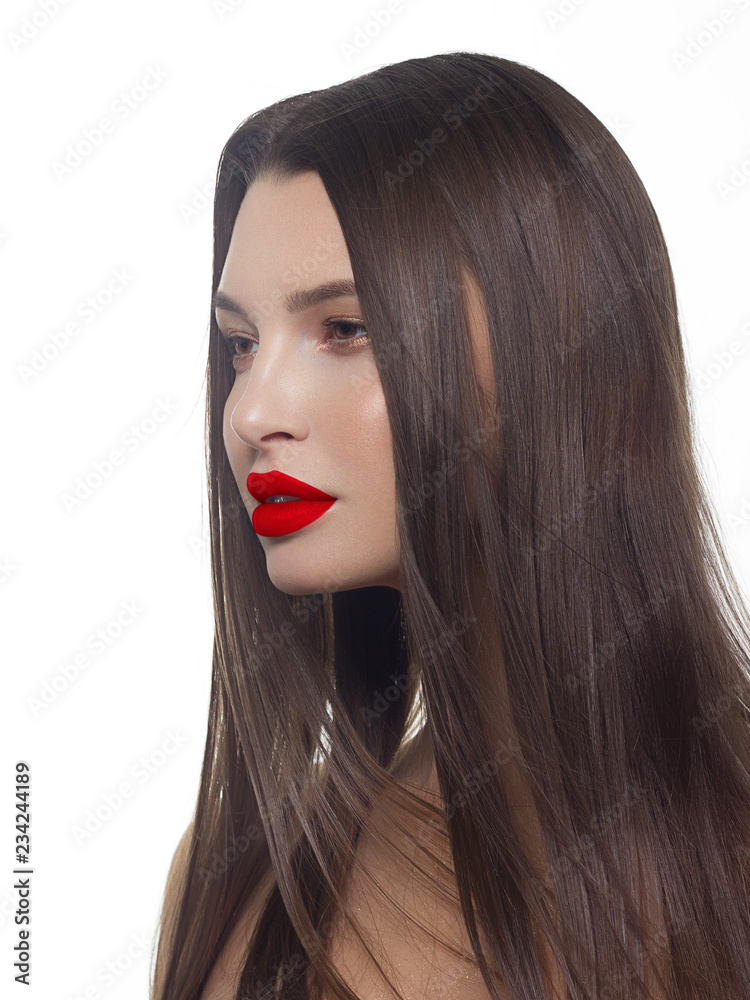 Fototapeta premium Close-up of beauty girl with long straight developing hair and radiant daytime makeup on her face. Skin care natural cosmetic in the spa salon or cosmetology. Red lipstick on the lips of a young woman