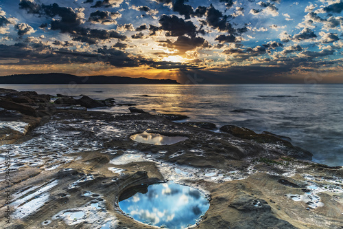 Sunrise Seascape with Clouds and Reflections in the Rock Pool