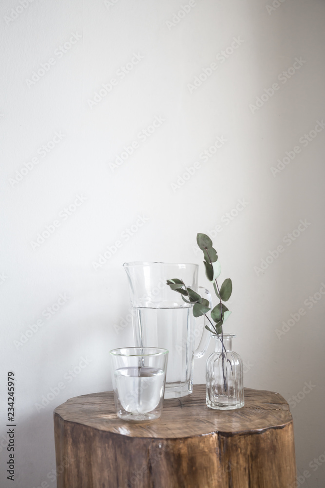 Nice still life and decoration with glass jar of water and eucalyptus plant in a wood small table