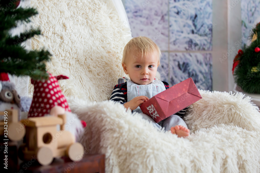 Fototapeta premium Little baby toddler boy, playing with christmas decoration at home, studio shot