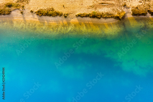 Abstract aerial image of a deep blue gravel lake in which sand is mined for the construction industry.