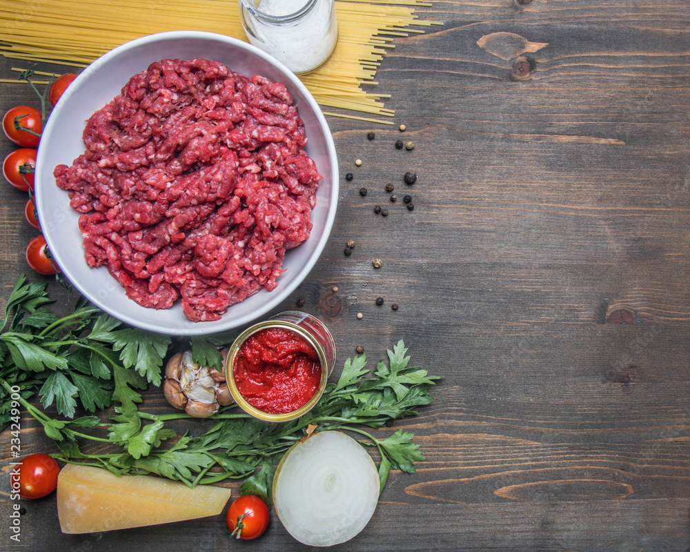 bolognese pasta cooking concept, raw minced meat, tomato paste, cherry tomatoes, pasta, parmesan, onions, garlic, herbs and herbs, oil and cold leaves on a rustic wooden background, place for text bolognese pasta cooking concept, raw minced meat, tomato paste, cherry tomatoes, pasta, parmesan, onions, garlic, herbs and herbs, oil and cold leaves on a rustic wooden background, place for text