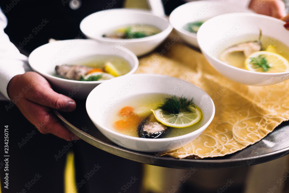 Four fish soups on the waiters tray Four fish soups on the waiters tray