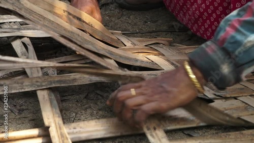 A steady, close-up shot of a person knitting dry palm leaves, to use them in construction. photo