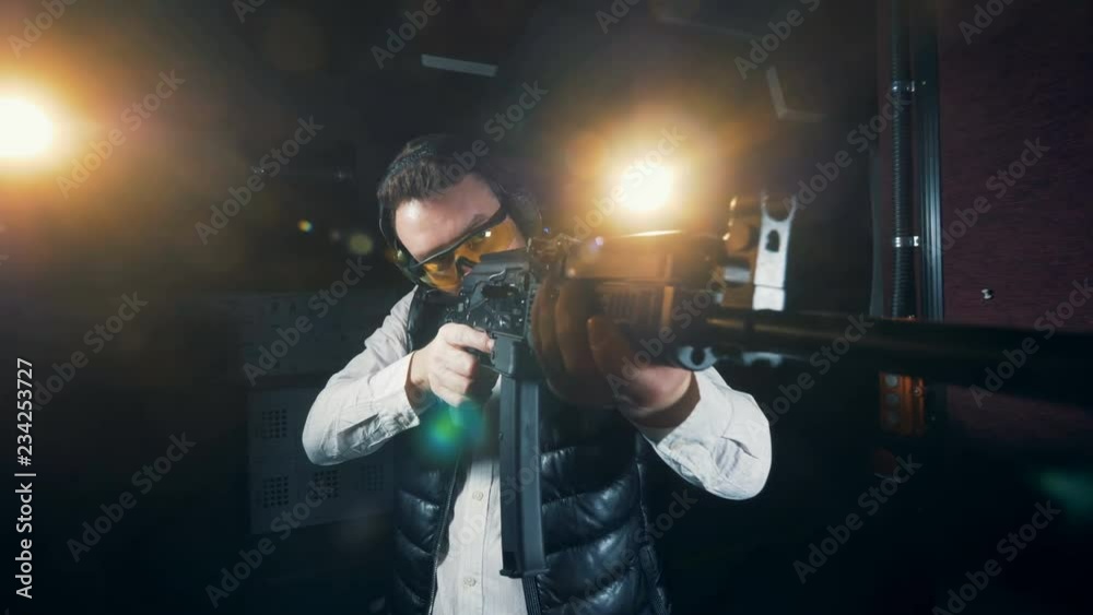 One man holding a big rifle at a shooting range, close up. One man holding a big rifle at a shooting range, close up.