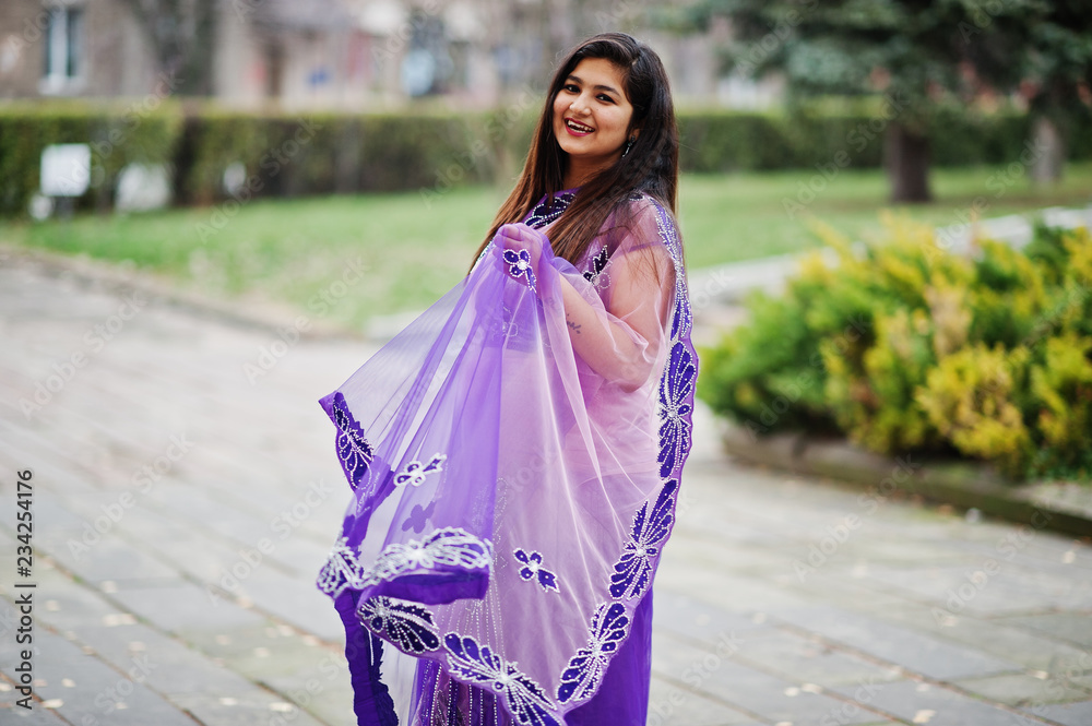 Indian hindu girl at traditional violet saree posed at autumn street.
