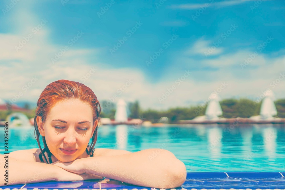 Woman looks out of the pool, hanging on the railing.