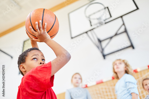 Afrikanischer Grundschüler wirft Basketball im Sportunterricht