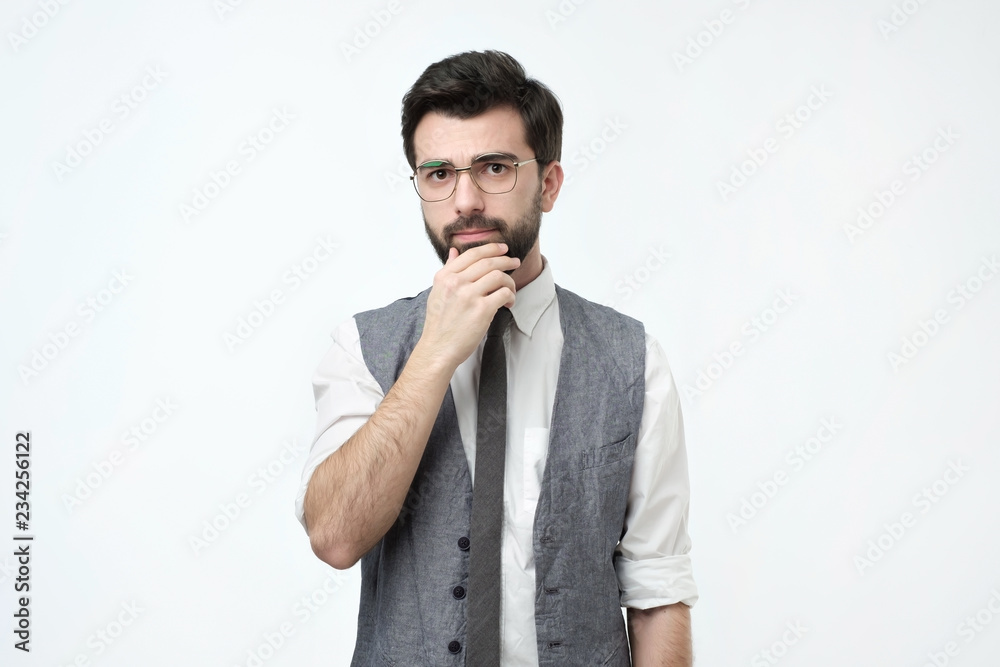 Handsome young hispanic man looking pensive while standing against white background Handsome young hispanic man looking pensive while standing against white background