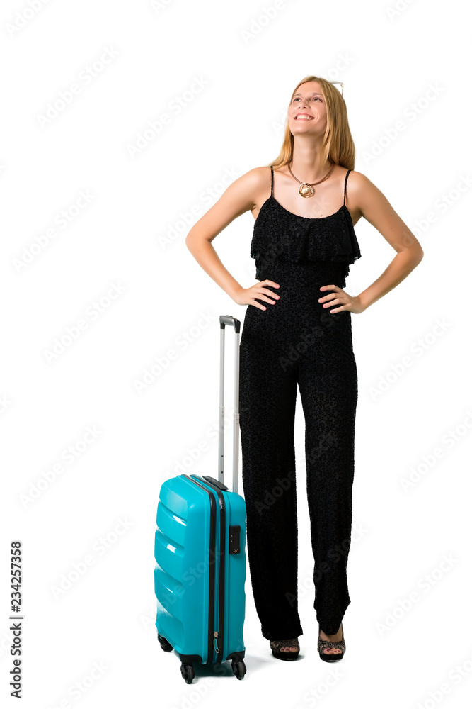 Blond girl traveling with her suitcase posing with arms at hip on isolated white backgroun Blond girl traveling with her suitcase posing with arms at hip on isolated white backgroun