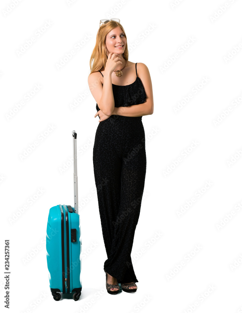 Blond girl traveling with her suitcase smiling a lot while putting hands on chest on isolated white backgroun Blond girl traveling with her suitcase smiling a lot while putting hands on chest on isolated white backgroun