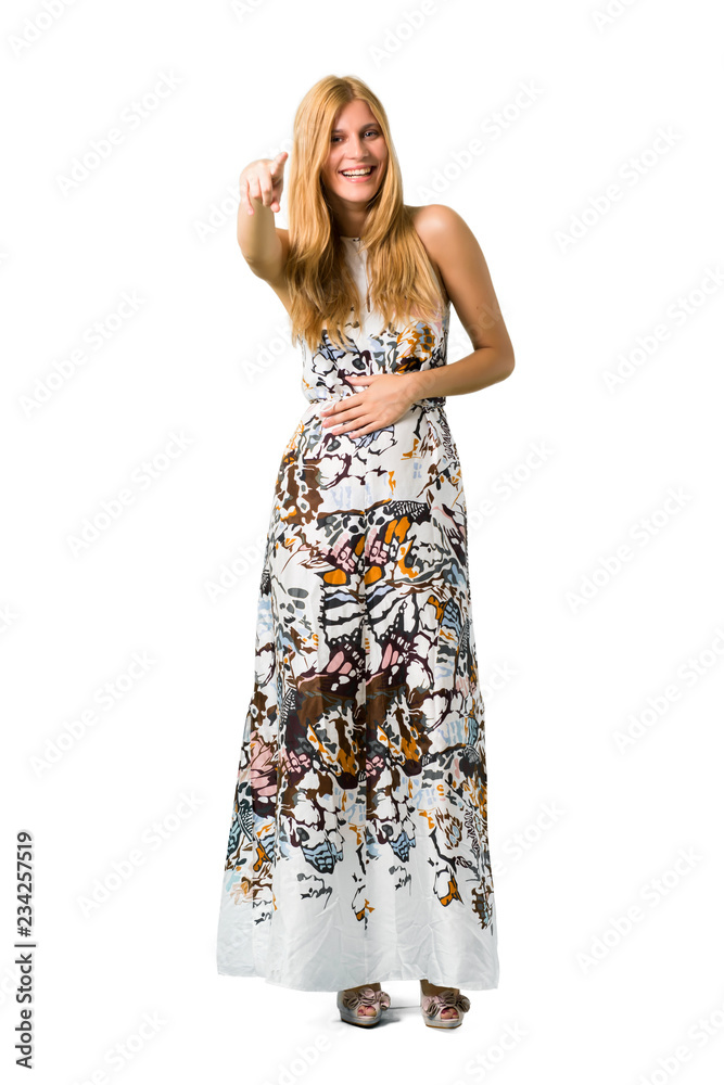 Blonde young girl in a summer dress pointing with finger at someone and laughing a lot on isolated white backgroun Blonde young girl in a summer dress pointing with finger at someone and laughing a lot on isolated white backgroun